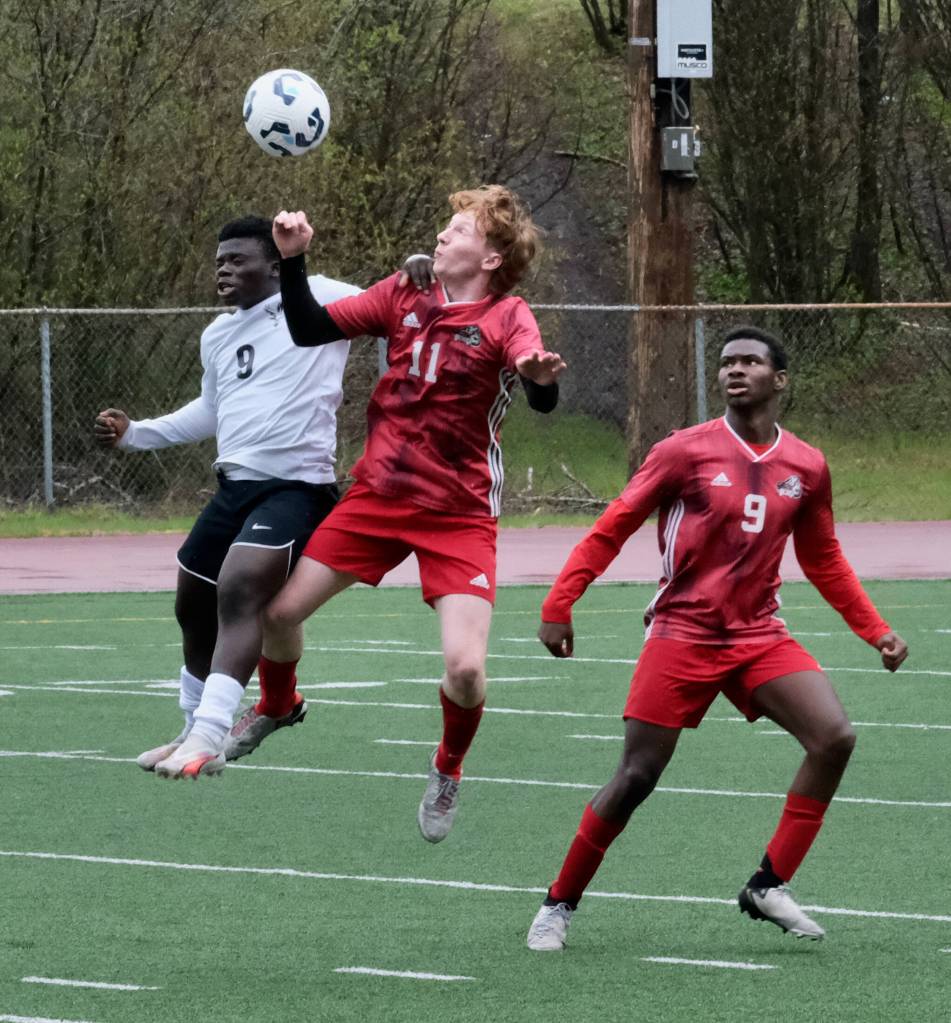 Juneau-Douglas High School: Yadaa.at Kalé junior Emmett Mesdag (11) and West Anchorage junior Musa Marrah (9) play a ball in the air as JDHS senior Ahmir Parker (9) looks on during the Crimson Bears 7-1 loss to the Eagles on Saturday at Adair Kennedy Memorial Park. (Klas Stolpe / Juneau Empire)