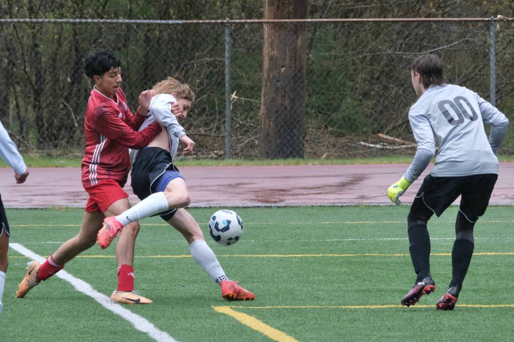 Juneau-Douglas High School: Yadaa.at Kalé junior Kevin Flores-Lopes battles West Anchorage senior McCarthy Barber (5) as West Anchorage sophomore keeper Kaleb Applegate (00) covers during the Crimson Bears 7-1 loss to the Eagles on Saturday at Adair Kennedy Memorial Park. (Klas Stolpe / Juneau Empire)