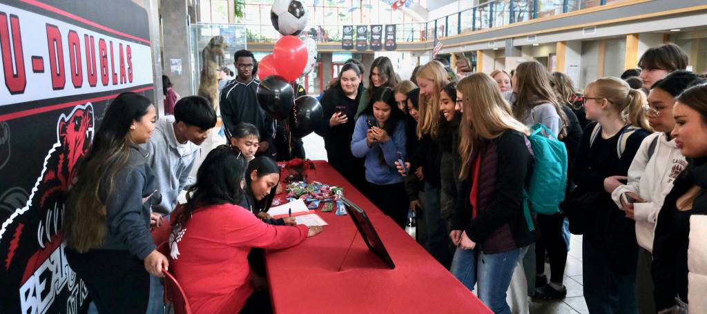 Family, friends and teammates of Juneau-Douglas High School: Yadaa.at Kalé senior Milina Mazon crowd in to watch her sign a Northwest Athletic Conference Letter of Intent on Monday in the JDHS commons to attend Edmonds College in Lynnwood, Washington, and play soccer for the Tritons. (Klas Stolpe / Juneau Empire)