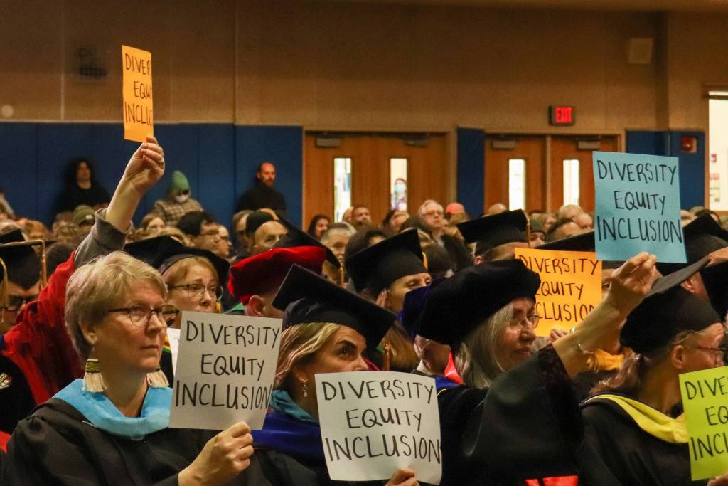 UAS faculty hold up Diversity, Equity and Inclusion signs at the University of Alaska Southeast commencement on Sunday, May 4, 2025. (Jasz Garrett / Juneau Empire)