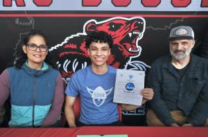 Juneau-Douglas High School: Yadaa.at Kalé senior Pedrin Saceda-Hurt signed an NCAA Division III student-athlete form on Wednesday in the JDHS commons to attend Luther College in Decorah, Iowa, and play for the Norse basketball team. At left is mother Nickie Saceda-Hurt and at right is father Frank Hurt. (Klas Stolpe/Juneau Empire)