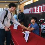 Juneau-Douglas High School: Yadaa.at Kalé sophomore Logan Carriker shakes hands with senior Pedrin Saceda-Hurt after Saceda-Hurt signed an NCAA Division III student-athlete form on Wednesday in the JDHS commons to attend Luther College in Decorah, Iowa, and play for the Norse basketball team. (Klas Stolpe/Juneau Empire)