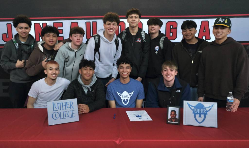 Juneau-Douglas High School: Yadaa.at Kalé senior Pedrin Saceda-Hurt signed an NCAA Division III student-athlete form on Wednesday in the JDHS commons to attend Luther College in Decorah, Iowa, and play for the Norse basketball team. Shown are friends and teammates attending. (Klas Stolpe/Juneau Empire)