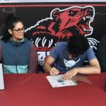 Juneau-Douglas High School: Yadaa.at Kalé senior Pedrin Saceda-Hurt signed an NCAA Division III student-athlete form on Wednesday in the JDHS commons to attend Luther College in Decorah, Iowa and play for the Norse basketball team. At left is grandmother Gethsemane Saceda, mother Nickie Saceda-Hurt and at right is father Frank Hurt. (Klas Stolpe/Juneau Empire)