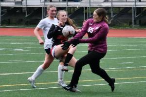 Juneau-Douglas High School: Yadaa.at Kalé junior Peyton Wheeler (5) has a shot stopped by Soldotna sophomore keeper Ryan Queen (55) as Stars senior Kendra Rose trails the play during the Crimson Bears 2-1 loss to the Stars on Thursday at Adair Kennedy Memorial Park. (Klas Stolpe/ Juneau Empire)