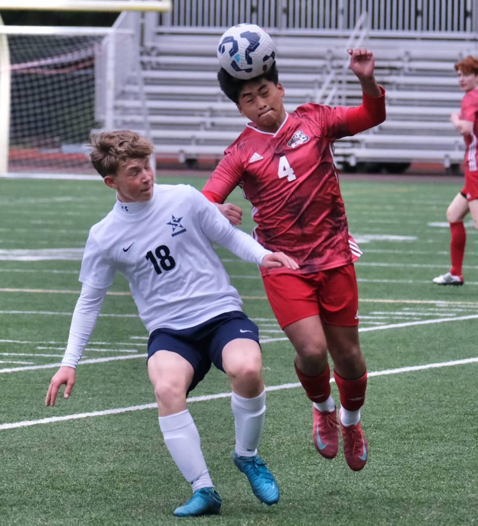 Juneau-Douglas High School: Yadaa.at Kalé sophomore Sam Mazon (4) heads a ball over Soldotna freshman Trevin Moore (18) during the Crimson Bears 3-0 win over the Stars on Thursday at Adair Kennedy Memorial Park. (Klas Stolpe / Juneau Empire)