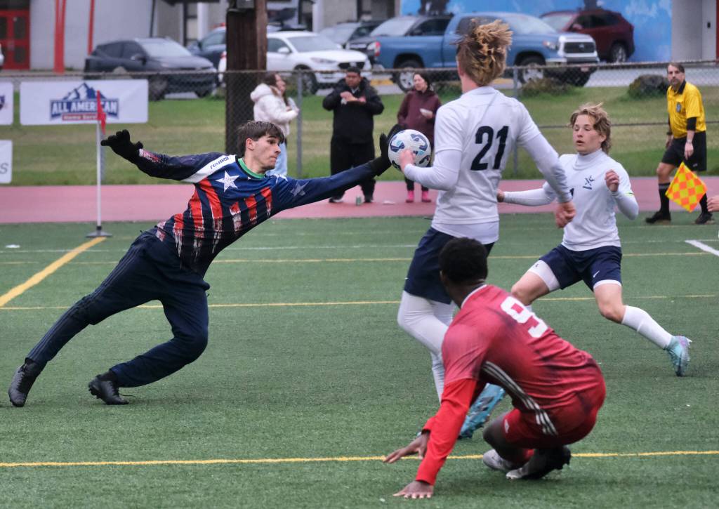 Soldotna junior keeper Luke Hillyer blocks a shot by Juneau-Douglas High School: Yadaa.at Kalé senior Ahmir Parker (9) as Soldotna junior Liam Peck (21) and senior Jonas Albrecht react during the Stars 3-0 loss to the Crimson Bears on Thursday at Adair Kennedy Memorial Park. (Klas Stolpe / Juneau Empire)
