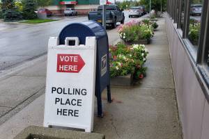 A sign posted on Aug. 18, 2024, outside of the Alaska Division of Elections office in Midtown Anchorage directs voters to the polling place inside. (Yereth Rosen/Alaska Beacon)