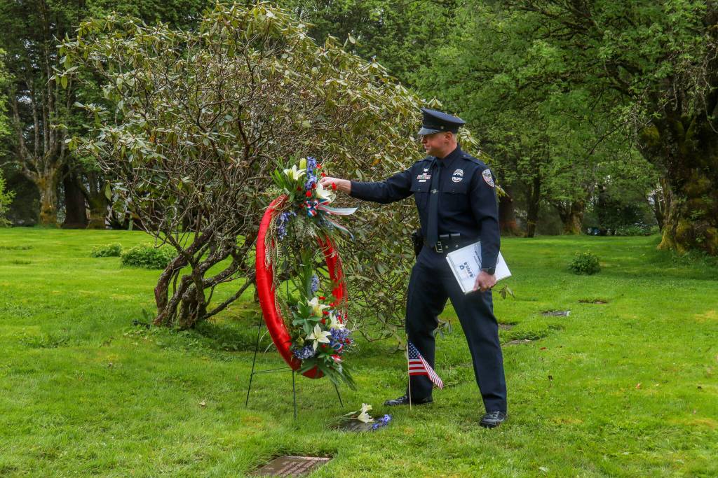 Juneau Police Department Detective Kirt-Stage Harvey stays after the ceremony to place flowers on the grave of fallen JPD officer Richard Adair. The two wreaths laid during the ceremony will reside at the JPD station and the Juneau Alaska State Troopers post. (Jasz Garrett / Juneau Empire)