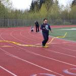 CJ Umbs crosses the finish line holding a torch during the Alaska Law Enforcement Torch Run on Saturday, May 17, 2025. (Ellie Ruel / Juneau Empire)