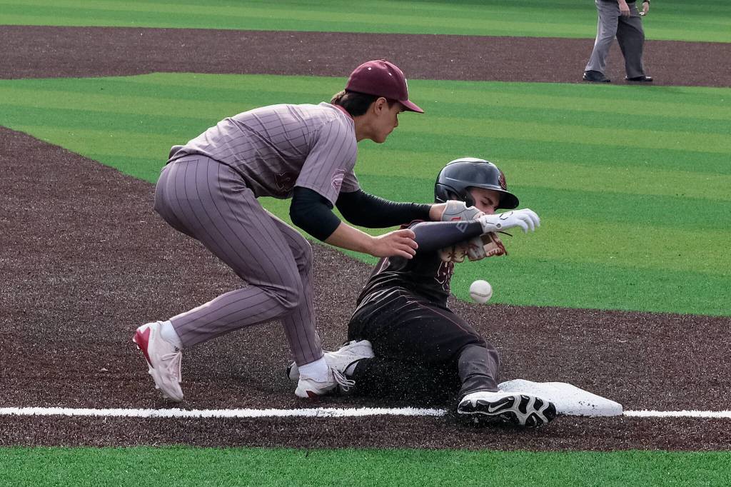 Juneau-Douglas High School: Yadaa.at Kalé junior Brandon Casperson slides and knocks the ball away from Ketchikan third baseman Owen Mendoza during the Crimson Bears baseball senior night against Ketchikan Saturday at Adair-Kennedy Memorial Park. (Klas Stolpe / Juneau Empire)
