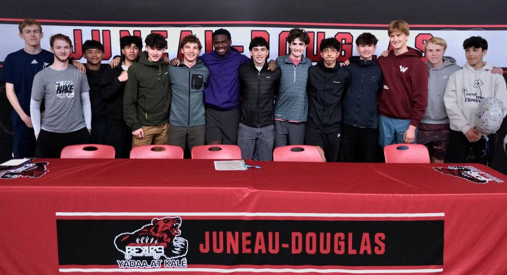 Juneau-Douglas High School: Yadaa.at Kalé senior Ahmir Parker, center, poses with Crimson Bears teammates after signing a letter of intent Thursday in the JDHS commons to attend Waldorf University in Forest City, Iowa, and play soccer for the Viking Warriors. (Klas Stolpe / Juneau Empire)