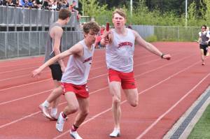 Juneau-Douglas High School: Yadaa.at Kalé senior Nick Iverson receives the 4x400 baton from classmate Finn Lamb during the Crimson Bears’ win in the final event of the Region V Championships on Saturday at Thunder Mountain Middle School. (Klas Stolpe / Juneau Empire)