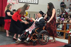 Hayden Aube is the first student to receive his diploma from Principal Paula Casperson during Juneau-Douglas High School: Yadaa.at Kalés graduation ceremony Sunday, May 25, 2025. Aube, a multisport star athlete for the Crimson Bears, was in a wheelchair after sustaining an injury Saturday competing in the Region V Track and Field Championships. (Mark Sabbatini / Juneau Empire)