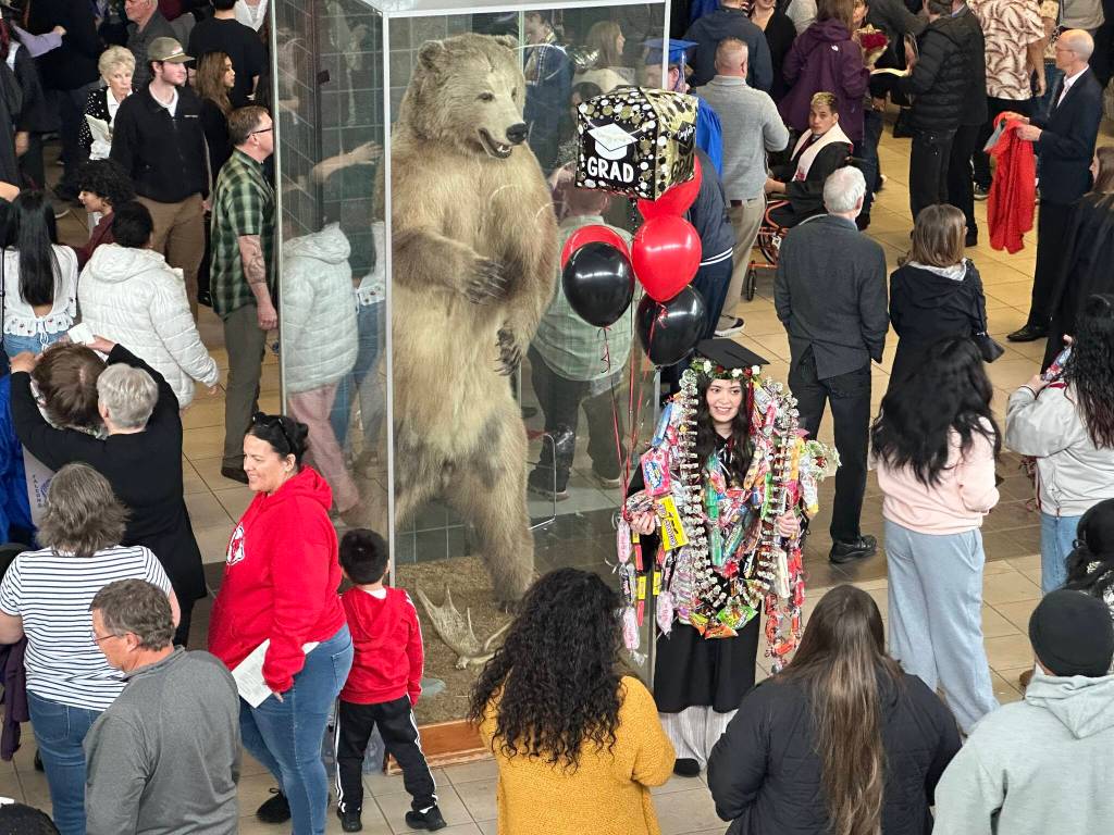 Tiare Maka, 18, poses for a photo next to Mac the Bear after graduating from Juneau-Douglas High School: Yadaa.at Kalés on Sunday, May 25, 2025. (Mark Sabbatini / Juneau Empire)