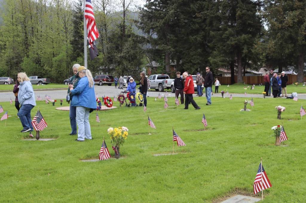 Community members visit graves and place flowers after the Juneau Memorial Day Service hosted by American Legion Auke Bay Post #25 at Alaskan Memorial Park on Monday, May 26, 2025. (Ellie Ruel / Juneau Empire)