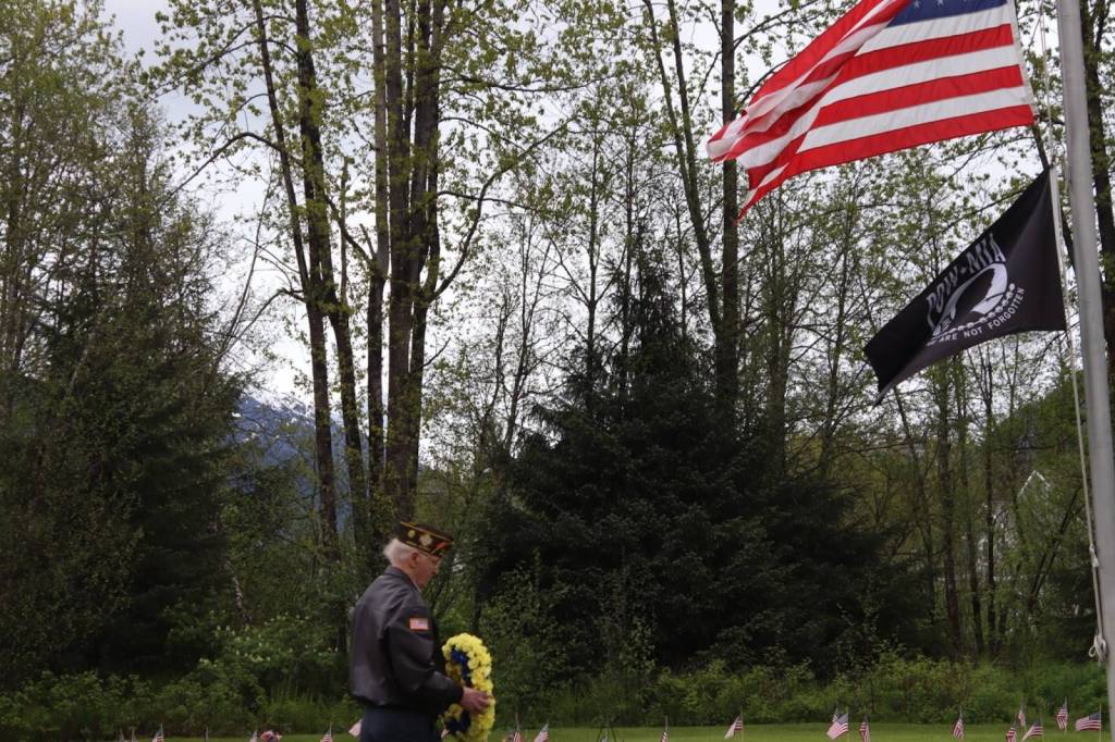 A volunteer places a wreath on a grave at the Juneau Memorial Day Service hosted by American Legion Auke Bay Post #25 at Alaskan Memorial Park on Monday, May 26, 2025. (Ellie Ruel / Juneau Empire)