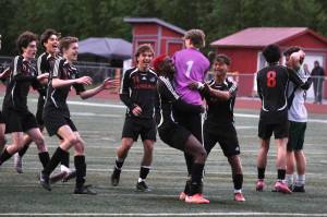 Juneau-Douglas High School: Yadaa.at Kalé Crimson Bears freshman goalkeeper Callen Walker (1) is swarmed by teammates after saving the final shot in a penalty shootout win over Service to open the 2025 ASAA/First National Bank Alaska Soccer State Championships at Wasilla High School on Thursday, May 29, 2025. Senior teammate Kellen Chester (8) consoles Service senior Matej Omalley (2). (Klas Stolpe / Juneau Empire)
