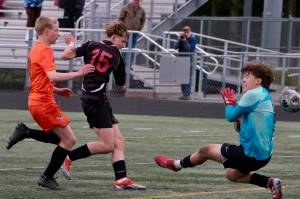 Juneau-Douglas High School: Yadaa.at Kalé freshman Bryce Haygood scores past West Anchorage sophomore defender Nathan Conlon and sophomore keeper Gideon Plikat during the Crimson Bears 3-2 loss in extra time to the Eagles in the 2025 ASAA/First National Bank Alaska Soccer State Championship semifinals Friday at Wasilla High School. (Klas Stolpe / Juneau Empire)