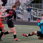 Juneau-Douglas High School: Yadaa.at Kalé freshman Bryce Haygood scores past West Anchorage sophomore defender Nathan Conlon and sophomore keeper Gideon Plikat during the Crimson Bears 3-2 loss in extra time to the Eagles in the 2025 ASAA/First National Bank Alaska Soccer State Championship semifinals Friday at Wasilla High School. (Klas Stolpe / Juneau Empire)