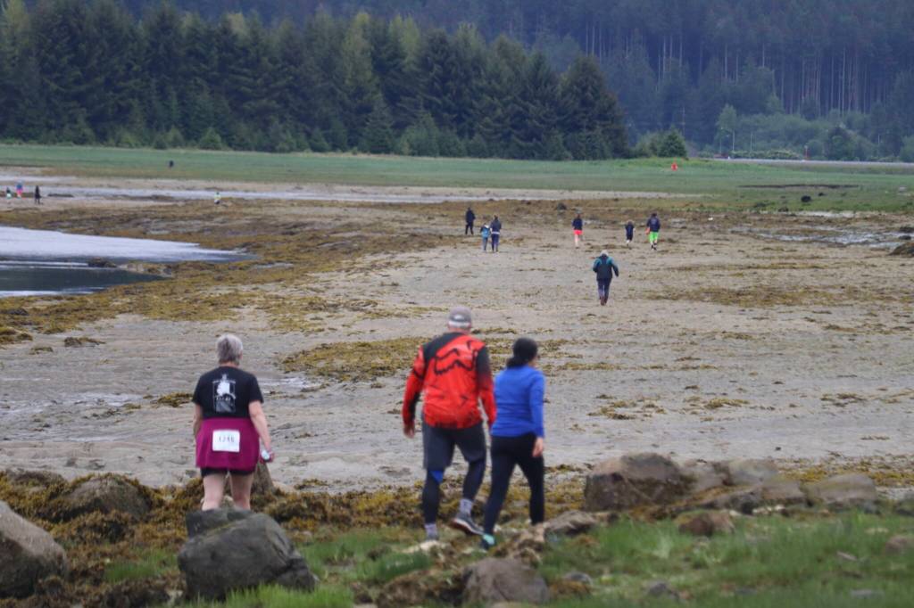 Runners make their way through sand and seaweed to the other side of Gastineau Channel at the 2025 Spring Tide Scramble on Saturday, May 31, 2025. (Ellie Ruel / Juneau Empire)