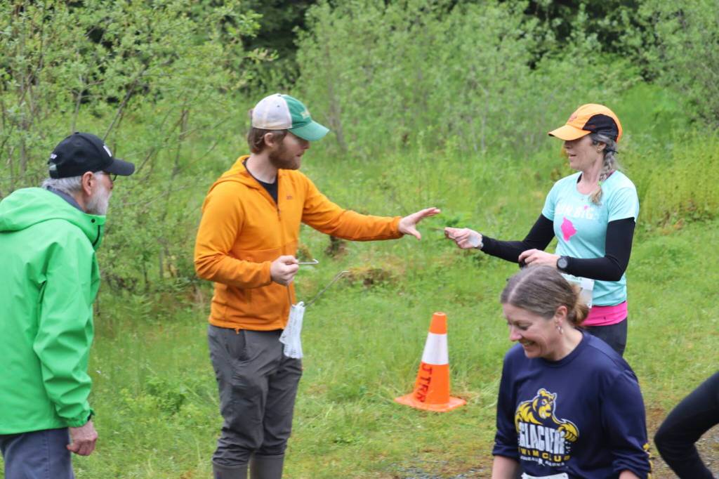 Melissa Anderson, 49, hands her race bib to a volunteer after crossing the finish line at the 2025 Spring Tide Scramble on Saturday, May 31, 2025. (Ellie Ruel / Juneau Empire)