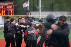 Juneau-Douglas High School: Yadaa.at Kalés Nate Fick is mobbed by team members after hitting a walk-off RBI single to give Juneau Douglas a 4-3 victory over Ketchikan on the second day of the Region V Baseball tournament at Norman Walker Field on Friday, May 30, 2025. (Christopher Mullen/Ketchikan Daily News)