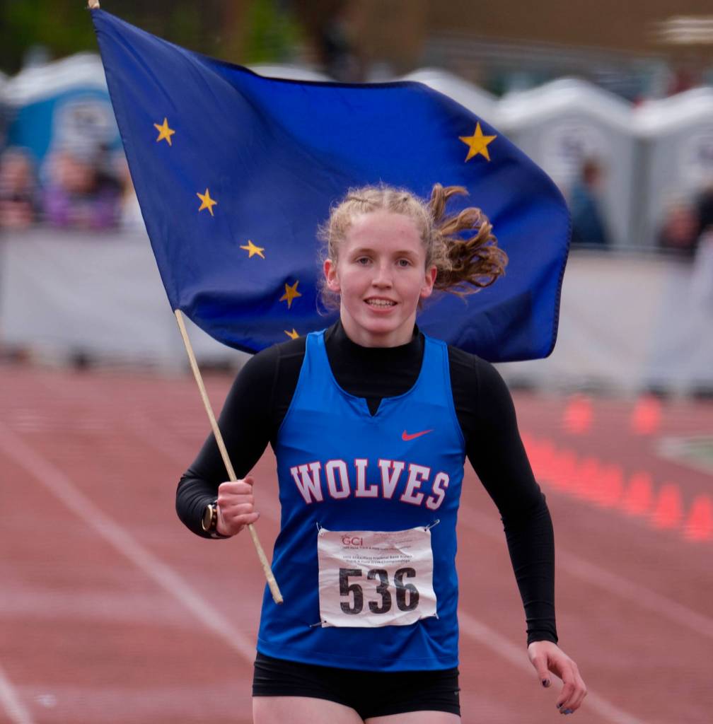 Sitka senior Clare Mullin carries the state championship flag for the last time in her high school career after winning the 800 meters during the 2025 ASAA/First Bank Alaska State Track & Field Championships on Saturday at Anchorages Dimond High School. (Klas Stolpe / Juneau Empire)