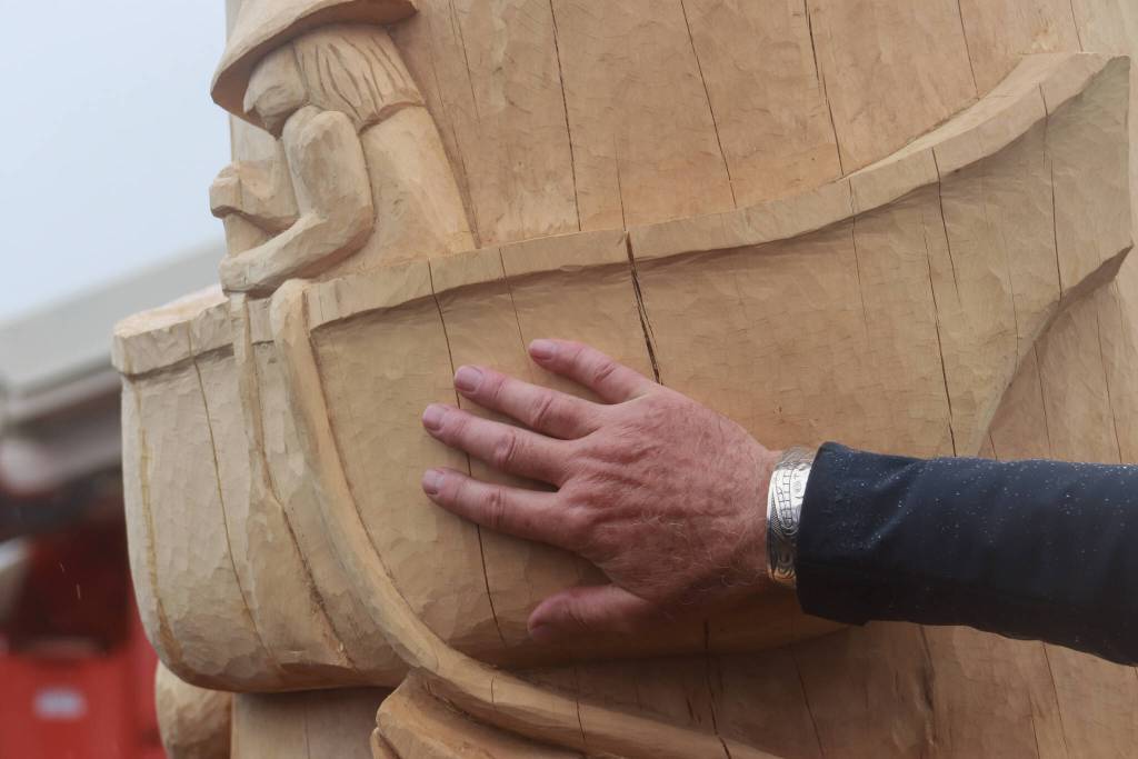 Lead carver Gordon Greenwald touches a carved Tlingit fisherman trolling in a canoe with what he called an old-fashioned lure. (Jasz Garrett / Juneau Empire)