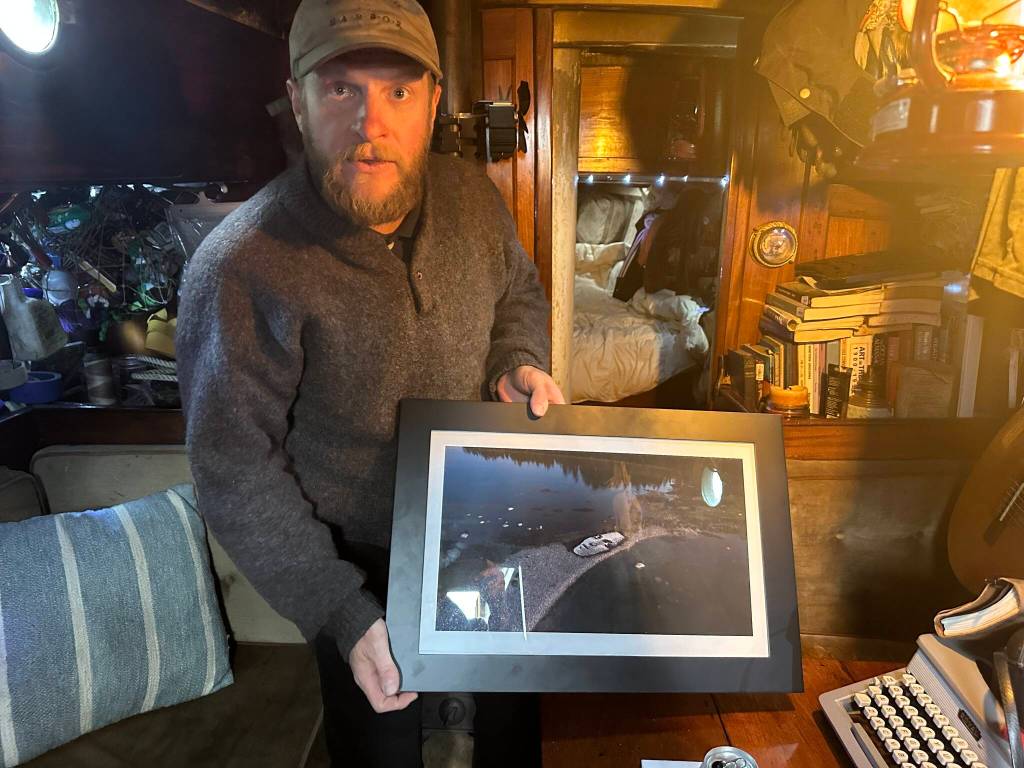Blake Byers shows a photo of one of his beach art projects aboard his boat in Juneau on Tuesday, June 3, 2025. (Mark Sabbatini / Juneau Empire)