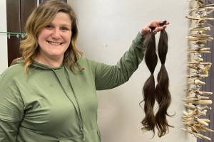 Kayla Hunt, owner of Salon 2211, holds a recent hair donation from customer Terry Kramarz that will be sent to the nonprofit organization Wigs for Kids. The two ponytails measure 20 and 22 inches each. (Laurie Craig / for the Juneau Empire)