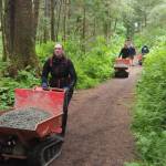 Volunteers push gravel up the Auk Nu Trail on Saturday, June 7, 2025. (Natalie Buttner / Juneau Empire)