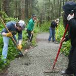Volunteers and Trail Mix staff spread gravel on the Auk Nu Trail on Saturday, June 7, 2025. (Natalie Buttner / Juneau Empire)