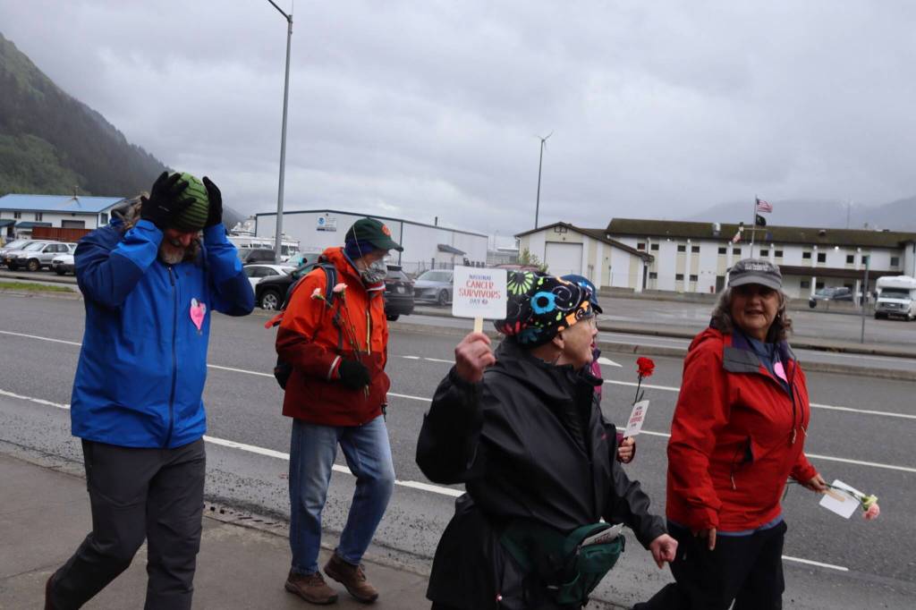 Walkers hold placards and flowers during the Cancer Survivors Day walk on Sunday, June 8, 2025. (Ellie Ruel / Juneau Empire)