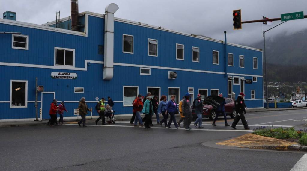 Cancer survivors and supporters cross Egan Drive at Merchants Wharf during the Cancer Survivors Day walk on Sunday, June 8, 2025. (Ellie Ruel / Juneau Empire)