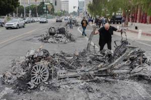 People inspect vehicles burned in Sunday’s protests against the Trump administration’s immigration crackdown in Los Angeles, Monday, June 9, 2025. Defense officials said a battalion of 500 Marines was “being mobilized” to help quell immigration protests in Los Angeles. Earlier, California leaders said they would sue President Trump for deploying National Guard troops. (Alex Welsh/The New York Times)