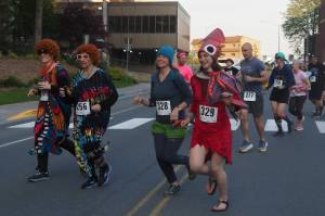 Runners cross Willoughby Avenue on Friday, June 20, 2025. Leading the pack are Adeline Souza and Heather Jones dressed as Mrs. Roper from the 1970s sitcom Threes Company. They were inspired by the nationwide phenomenon Mrs. Roper Romps. (Natalie Buttner / Juneau Empire)