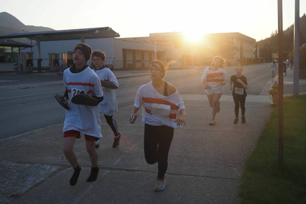 Members of the decagon of bowling pins run in the late night sun on Friday, June 20, 2025. On the right is Neve McNamara, the bowling ball. (Natalie Buttner / Juneau Empire)