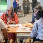Bridget Smith (left) helps new U.S. citizens register to vote following the naturalization ceremony on Tuesday, June 24, 2025. (Jasz Garrett / Juneau Empire)