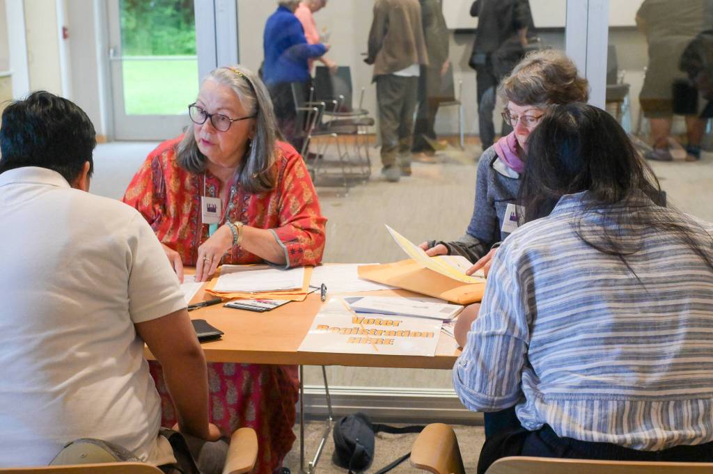 Bridget Smith (left) helps new U.S. citizens register to vote following the naturalization ceremony on Tuesday, June 24, 2025. (Jasz Garrett / Juneau Empire)