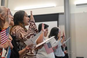 Those whose naturalization applications were approved on Tuesday, June 24, 2025, take the naturalization oath of allegiance that evening in the Mendenhall Valley Public Library. (Jasz Garrett / Juneau Empire)
