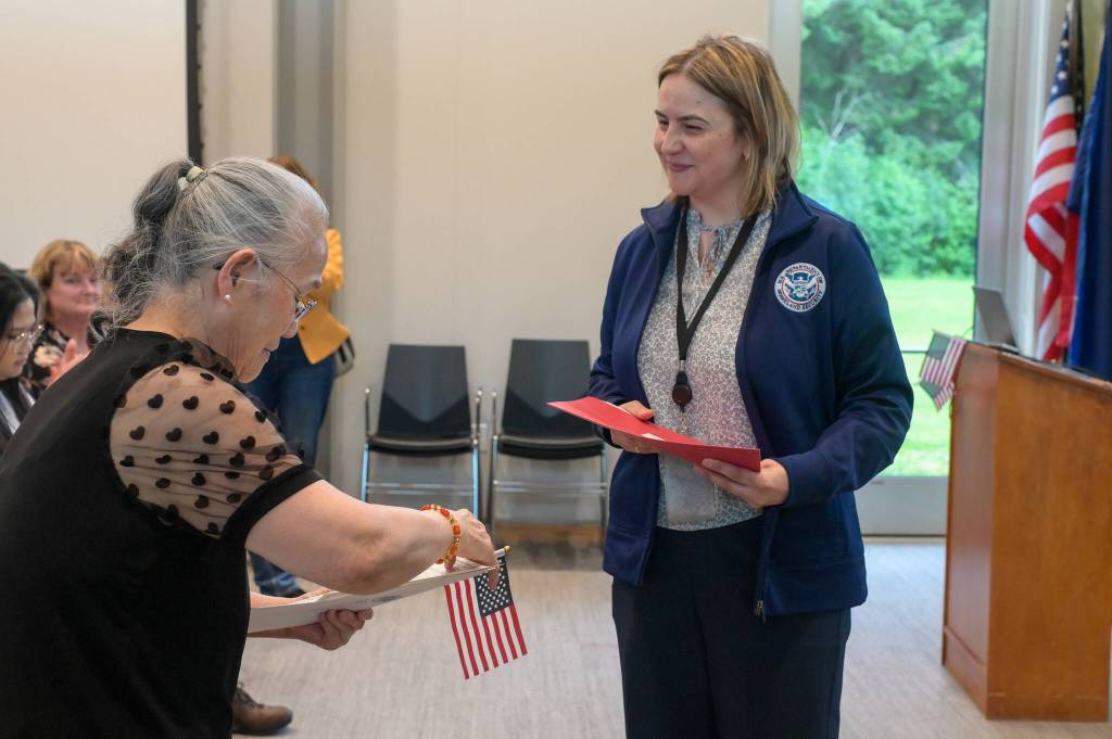Quang Le receives her certificate of naturalization from Ludmila Postolachi, an immigration services officer, on Tuesday, June 24, 2025. (Jasz Garrett / Juneau Empire)