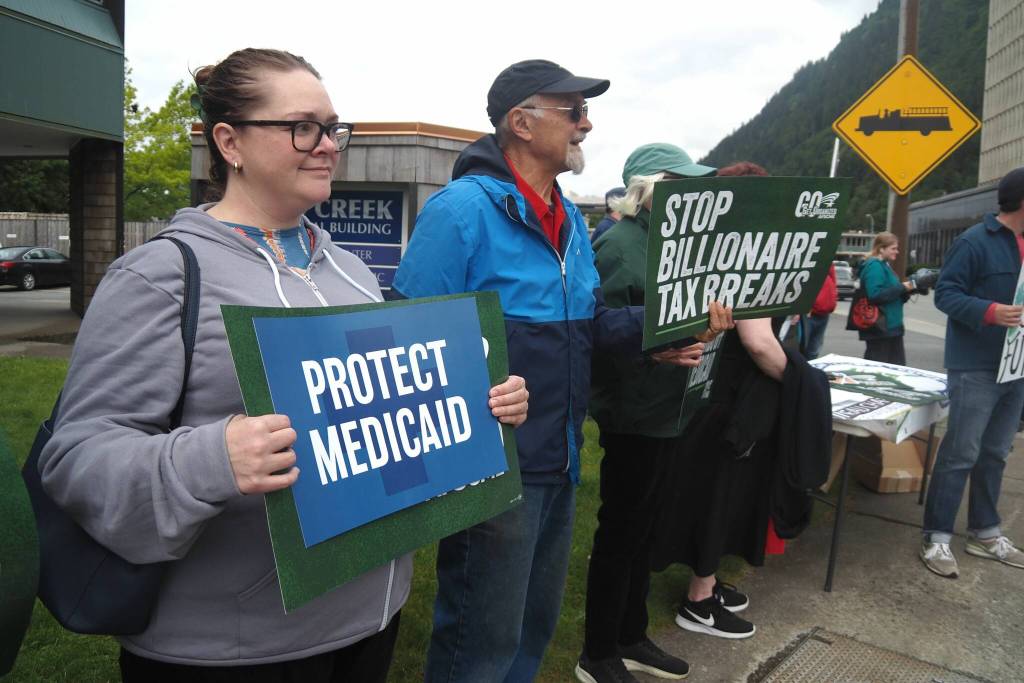 Demonstrators hold signs outside state senators offices on Friday, June 27, 2025. (Natalie Buttner / Juneau Empire)
