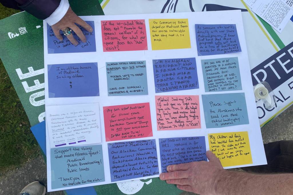 Demonstrators paste written accounts of their experiences with Medicaid on a poster board on Friday, June 27, 2025. (Natalie Buttner / Juneau Empire)