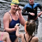 Kristan Jones takes a flower from daughter Aubrey Villa after winning Saturdays third race of the Open Water Swim Series on Auke Lake. (Klas Stolpe / Juneau Empire)