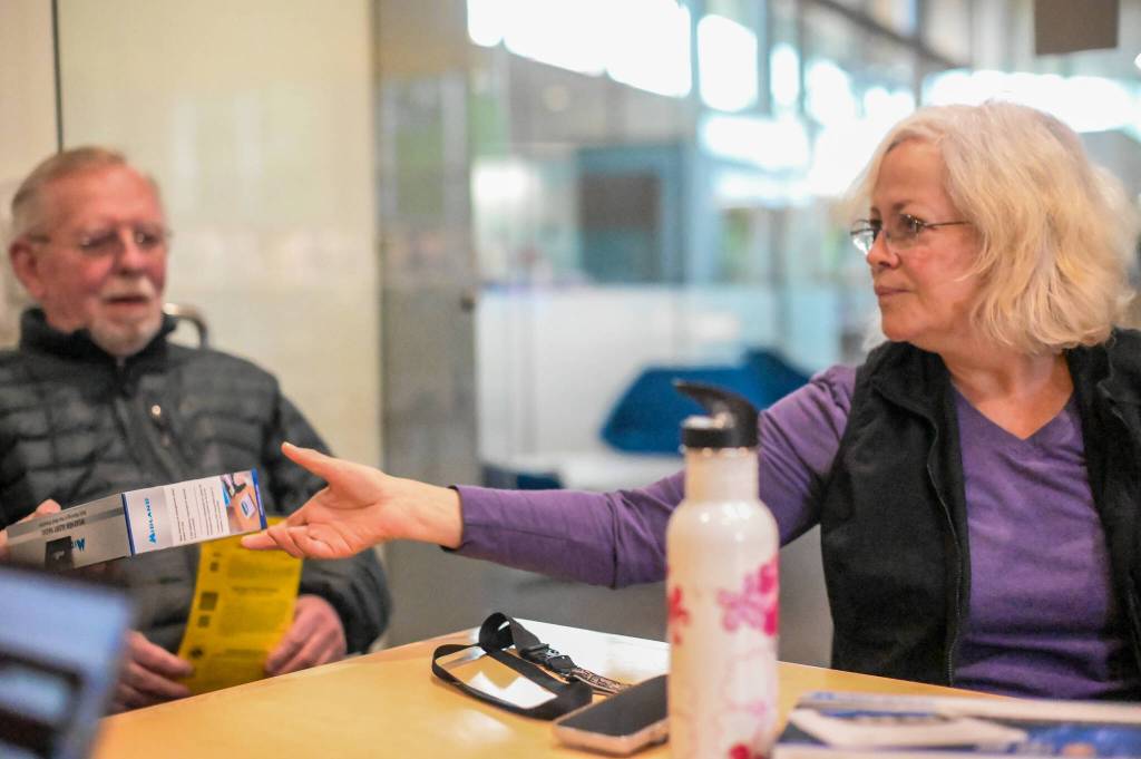 Lori Stedman (right) hands out a National Oceanic and Atmospheric Administration Weather Alert Radio provided by the Juneau Lions Club to those attending a Juneau Flood Solution Advocates meeting on Thursday, June 26, 2025. (Jasz Garrett / Juneau Empire)