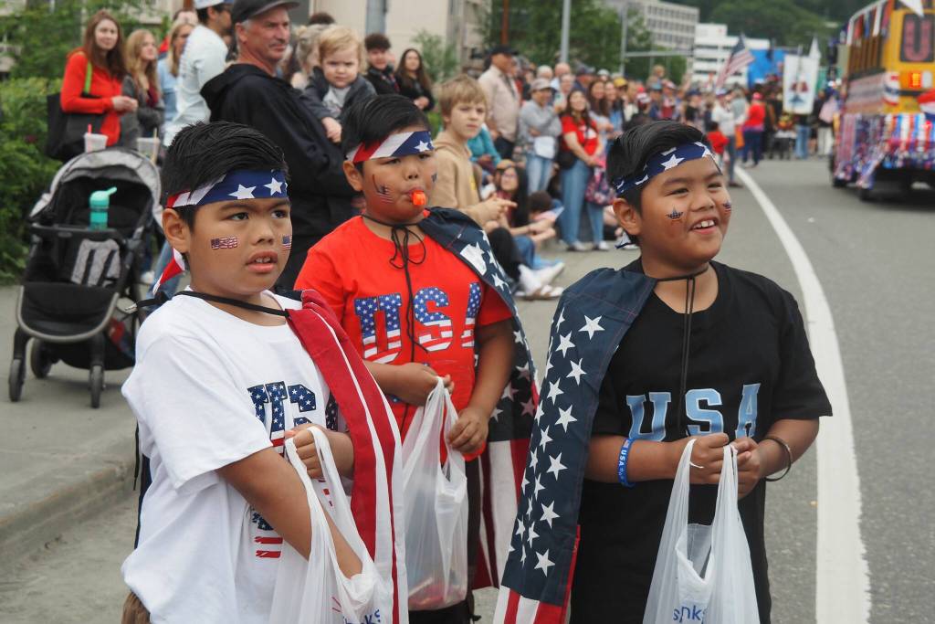 Triplets Lawrence, Liam, and Logan David wait excitedly for the next float to pass by them during the 2025 downtown Juneau Fourth of July Parade. (Natalie Buttner / Juneau Empire)