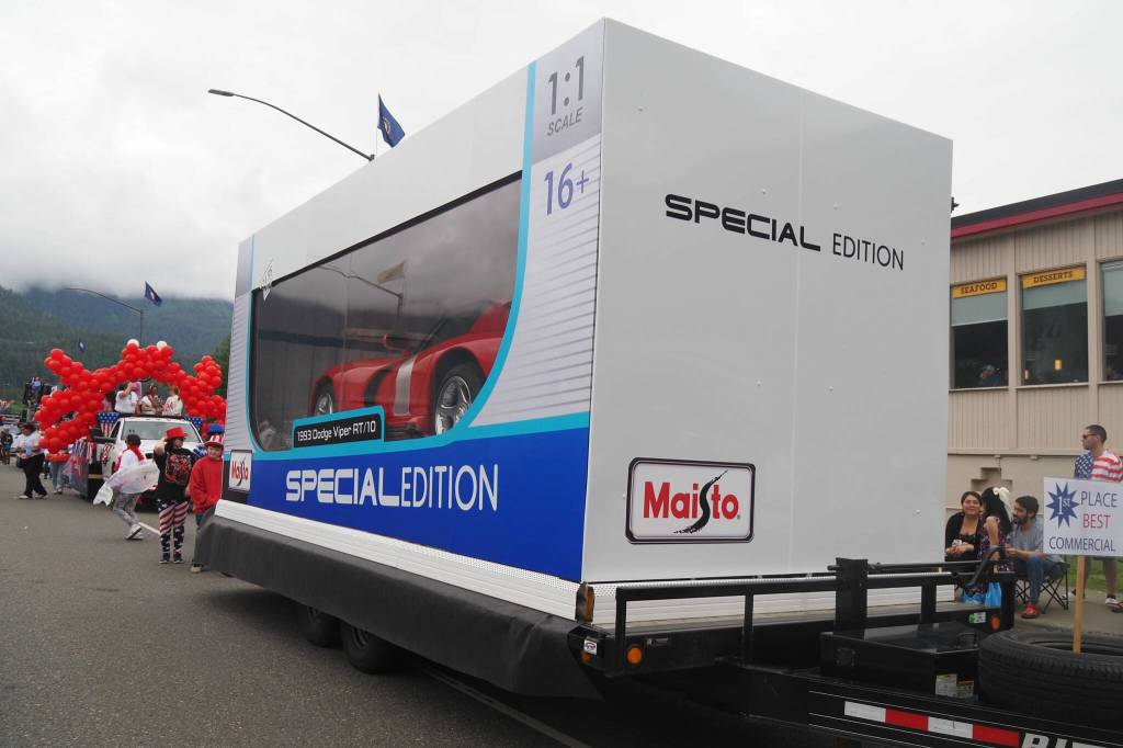 The Affordable Auto Sales float, a one-to-one replica of a Maisto remote-control car box with a real car inside impresses crowds as it travels down Egan Drive during the 2025 downtown Juneau Fourth of July parade. (Natalie Buttner / Juneau Empire)
