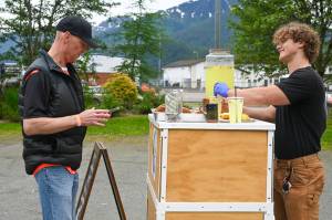 Andy Engstrom (left) uses bitcoin to buy lemonade and cookies from business owner Denali Schijvens (right) on Saturday, July 5, 2025. (Jasz Garrett / Juneau Empire)