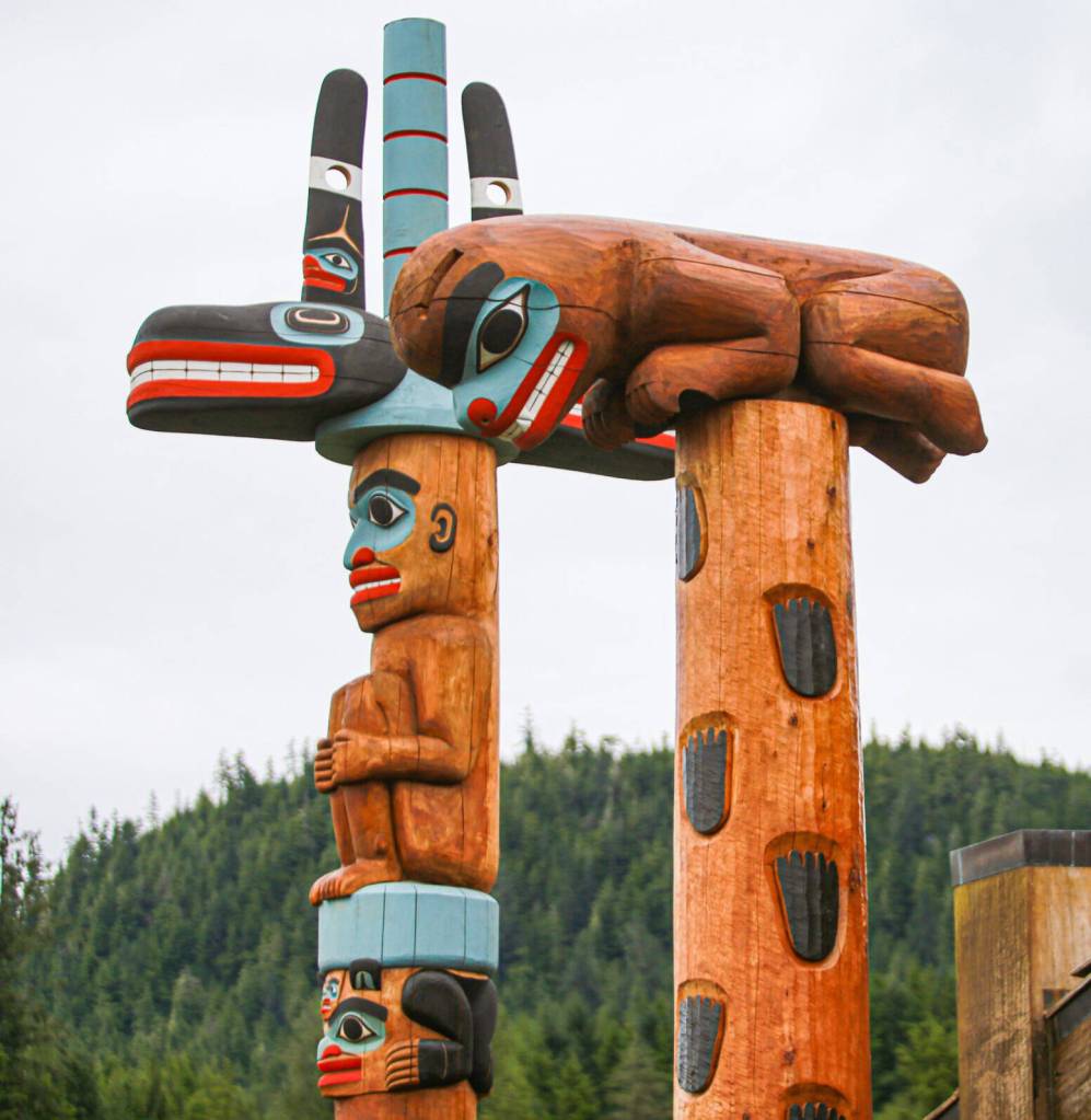 The Bear Up The Mountain and the Gunakaadeit poles stand next to each other after being raised in front of Chief Shakes House. The poles were set in place earlier in the week, in advance of the ceremonies that started on Thursday, July 17. Photo by Jonathon Dawe / Wrangell Sentinel